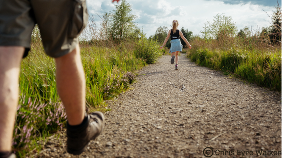 Jeunes filles courant devant un homme adulte sur un chemin du Parc naturel